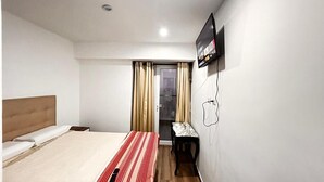 A hotel room with a bed, a TV, a small table, and a window with curtains. - Departamento con Vista al Mar (Lima)