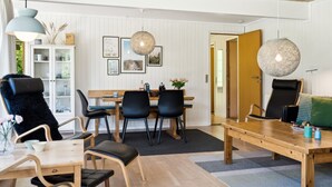 A modern dining area with a wooden table and chairs, a white cabinet with glass doors, and a large hanging light fixture. - "Aleta" - 600m from the sea by Interhome (Grenaa)