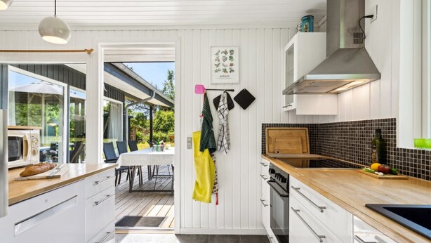 A modern kitchen with white cabinetry, a wooden countertop, and a view to the outdoors. - "Aleta" - 600m from the sea by Interhome (Grenaa)
