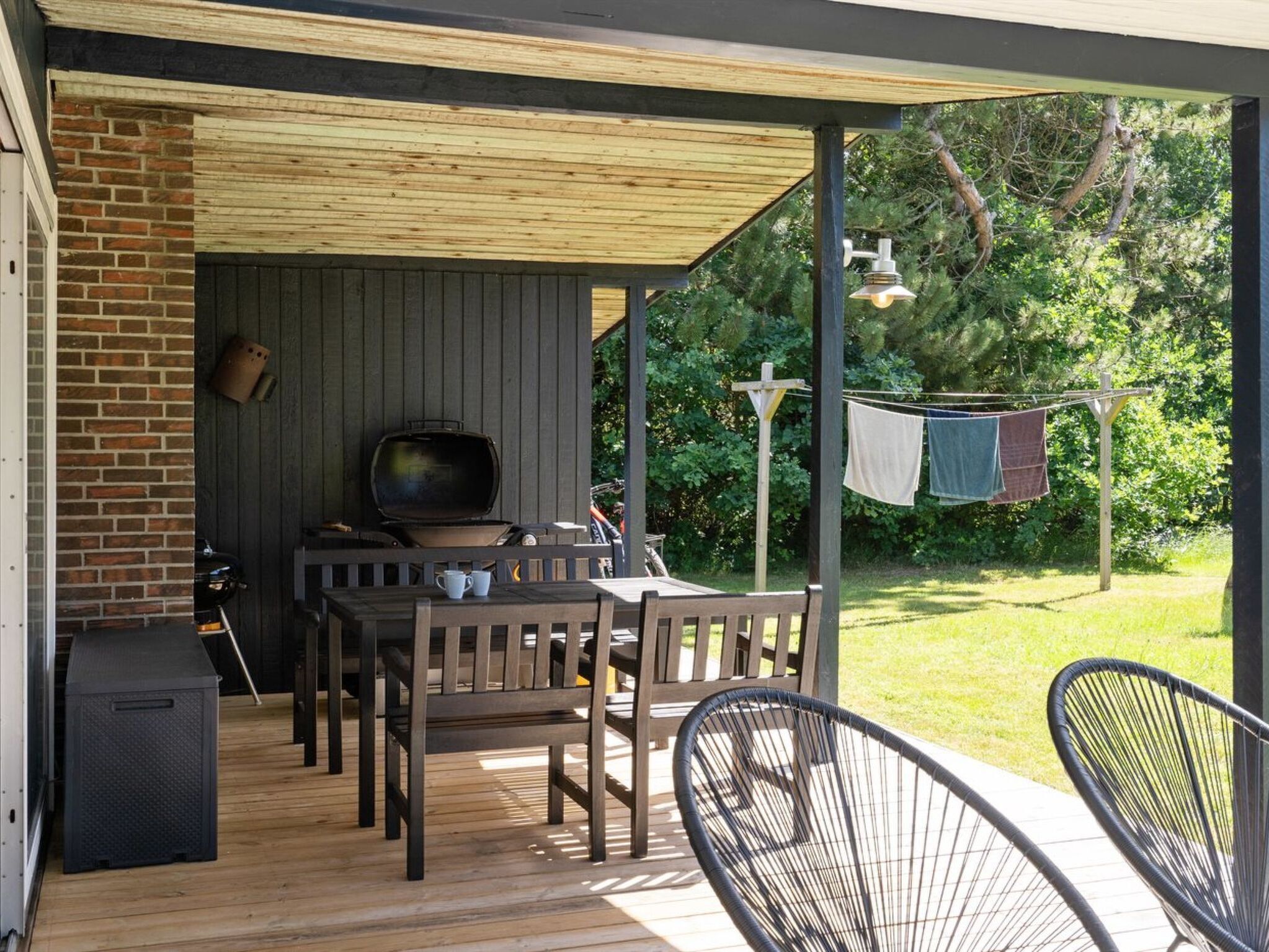 A covered outdoor patio with a grill, seating, and a TV.