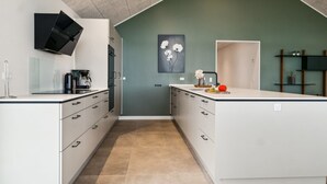 Une cuisine moderne avec des meubles blancs, une hotte noire et un grand îlot central doté d’un évier.