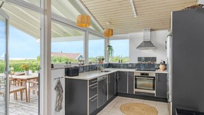A modern kitchen with large windows, a built-in oven, and a view of the outdoors. - "Gedda" -  from the sea by Interhome (Vestervig)