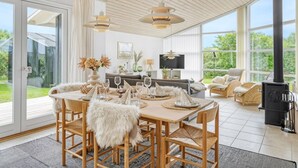 A spacious dining area with a large table set for six, surrounded by wicker chairs with fur throw cushions. - "Gedda" -  from the sea by Interhome (Vestervig)