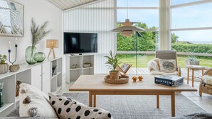 A modern living room with a large window, a flat-screen TV, and a cozy seating area with a coffee table. - "Gedda" -  from the sea by Interhome (Vestervig)
