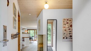 Een gang met een houten plafond, een deur met een sleutelgat, een wandlamp en een poster met vissen.
