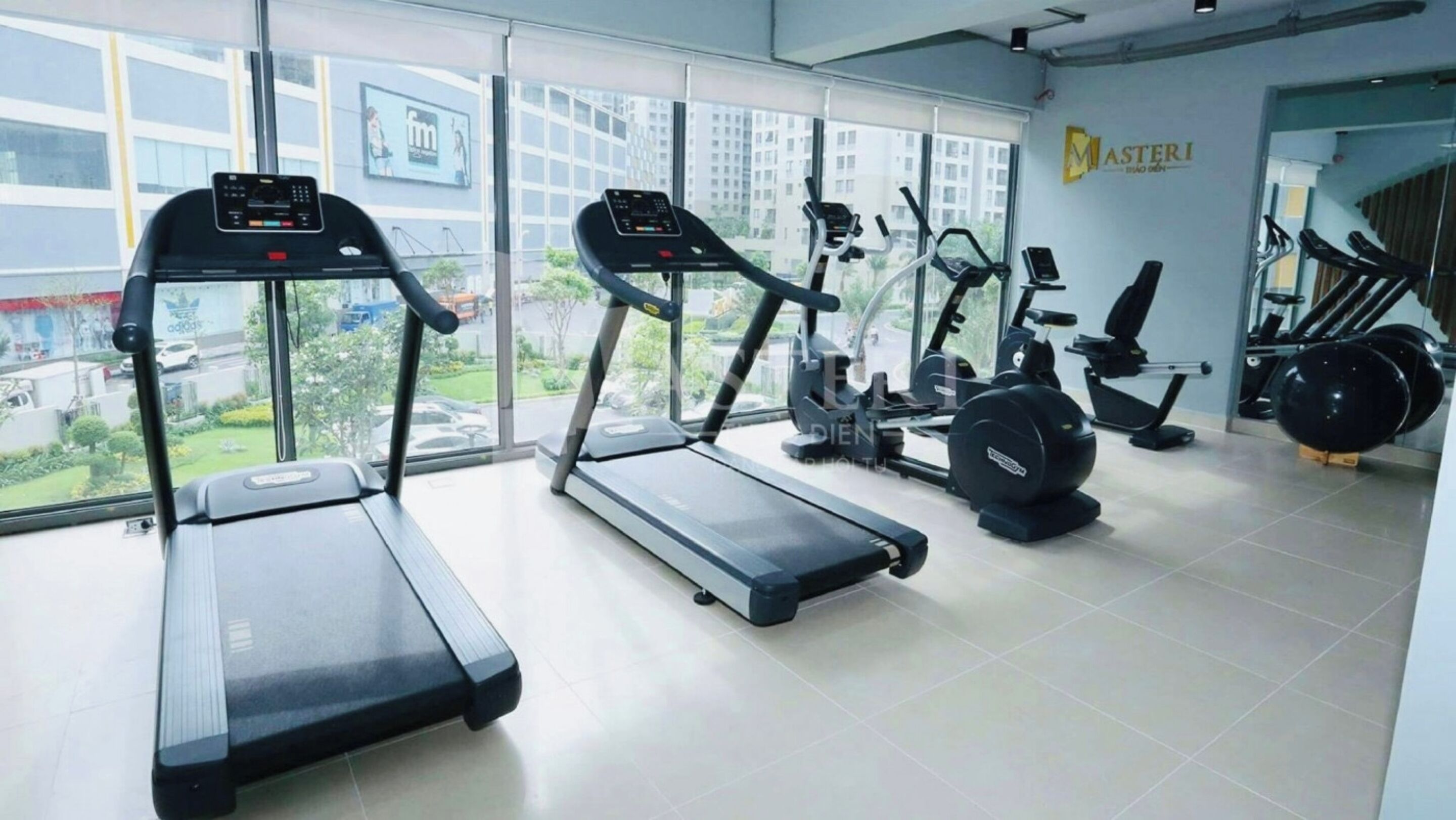 Un gimnasio con cintas de correr, bicicletas estáticas y pelotas de ejercicio.
