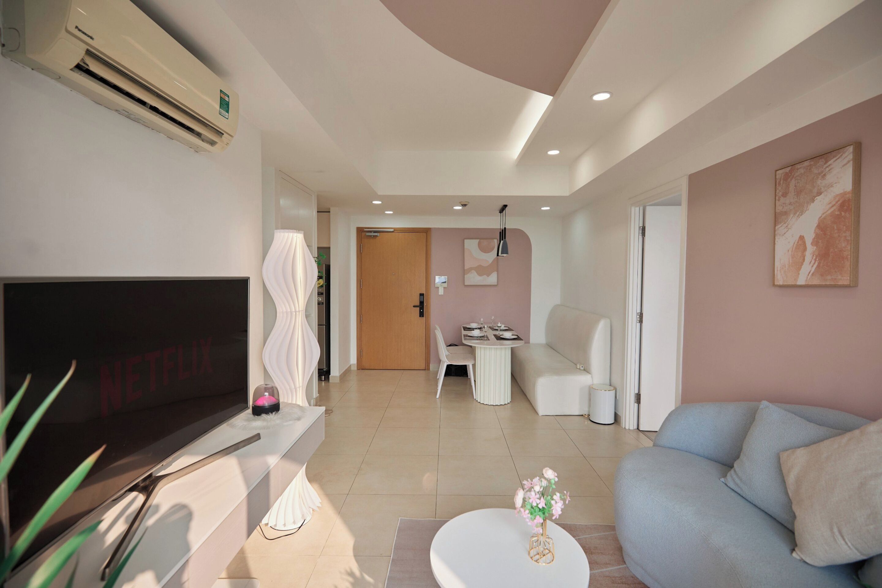 Uma sala de estar moderna com uma televisão de tela plana, um sofá, uma mesa de centro e um espaço de jantar com cadeiras e uma mesa.