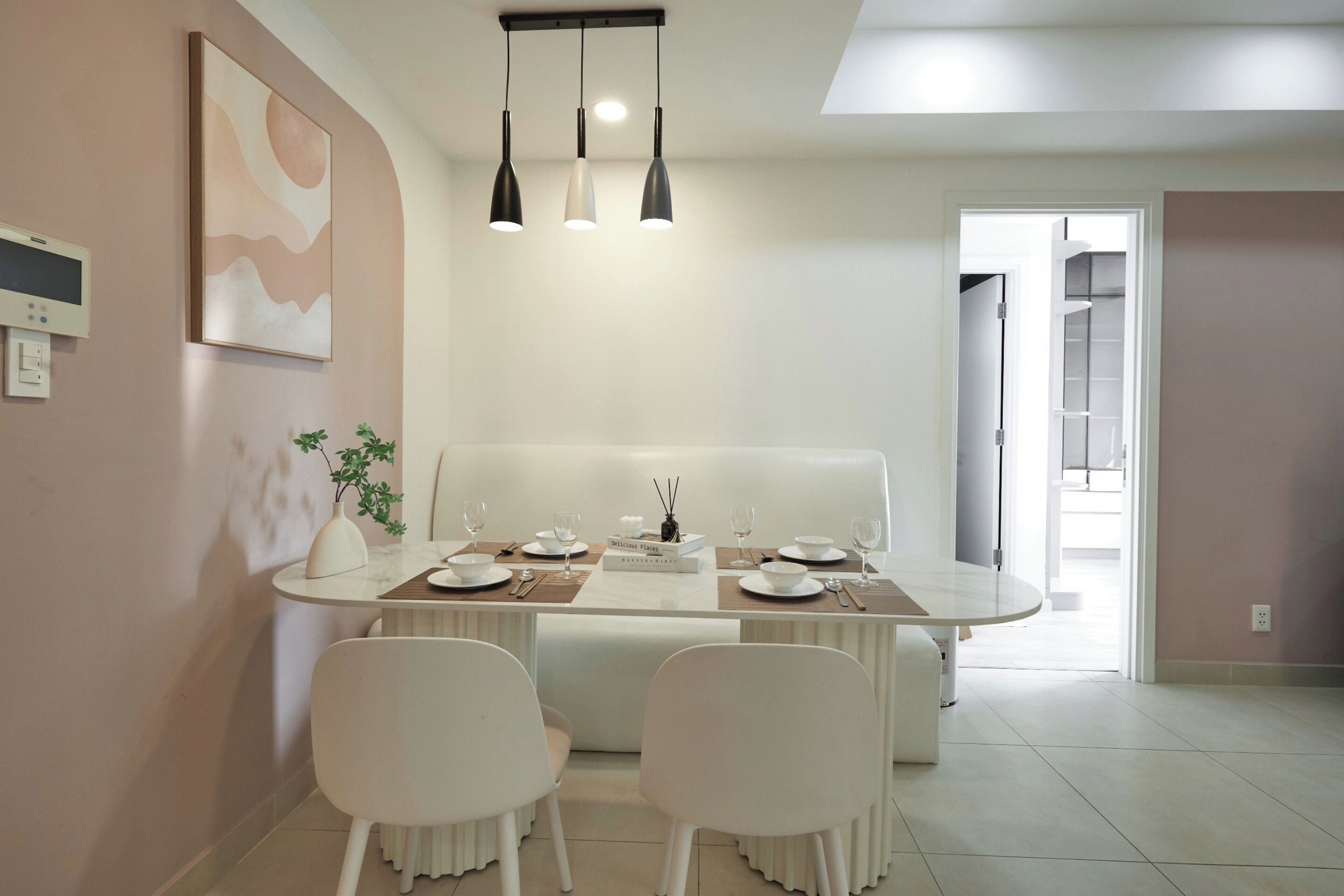 A modern dining area with a white table set for four, a bench, and a white chair.