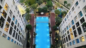 A high-rise building with a central swimming pool surrounded by greenery and balconies. - The MASTERI ANGIA Prestige Suite By An Gia Hospitality (Ho Chi Minh City)