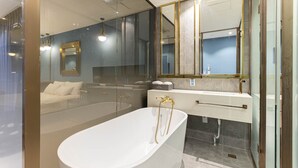 A modern bathroom with a freestanding bathtub, a large mirror, and a glass shower enclosure. - Hotel Des Arts (Seoul)