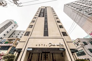 Een hotel met een modern design, herkenbaar aan een opvallende ingang en een bord met daarop de vermelding 'hotel'.