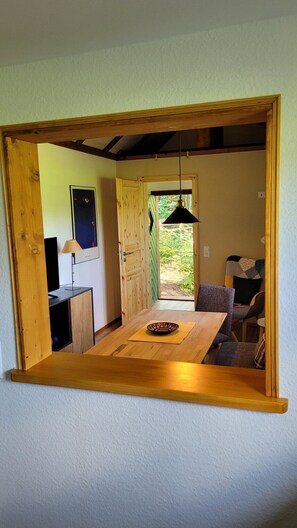 A room with a wooden table, a chair, a television, and a door leading outside.