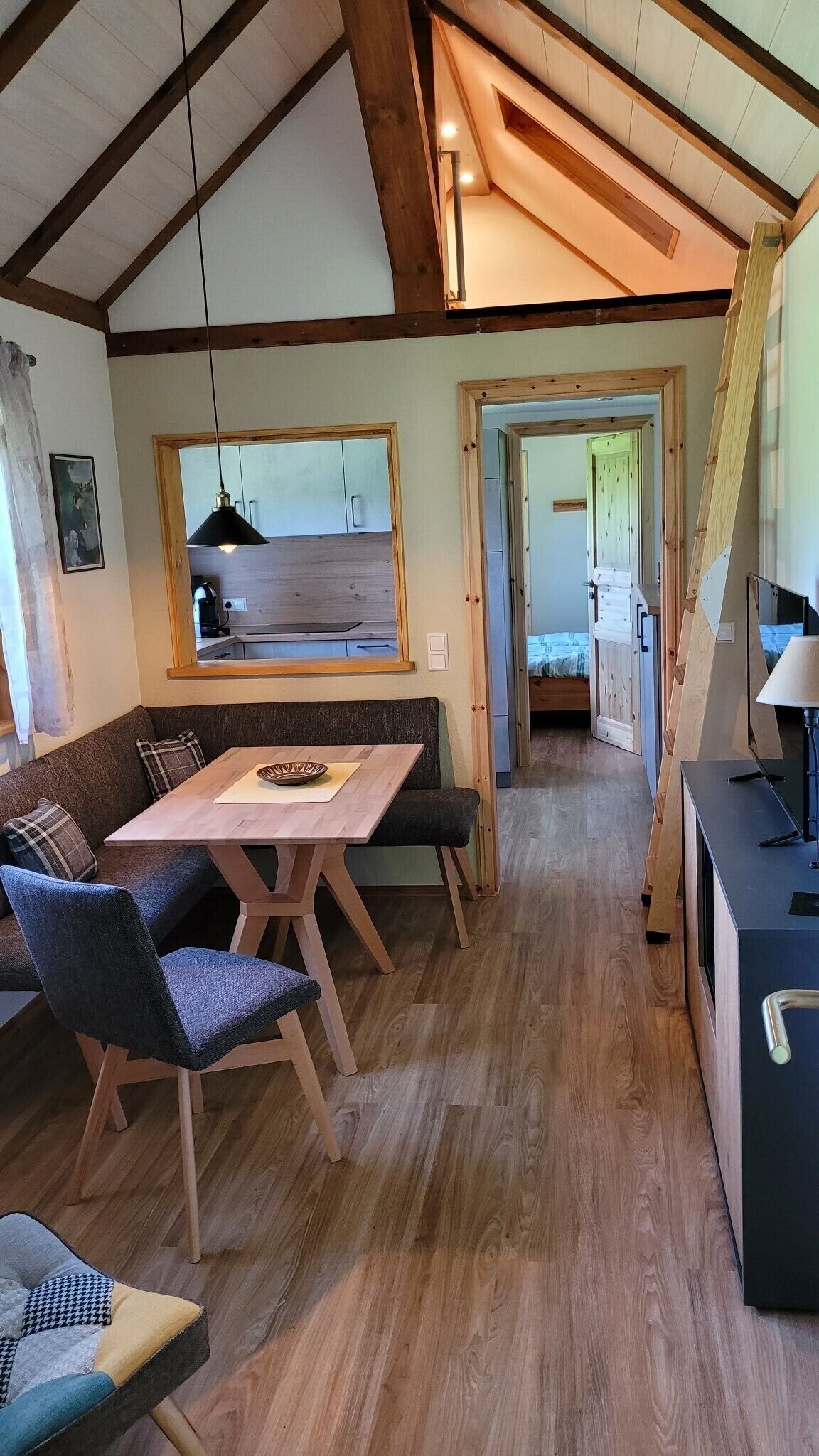Ein gemütliches Interieur mit einem Holzespeisetisch, Stühlen, einer Couch und einer Küchenzeile.