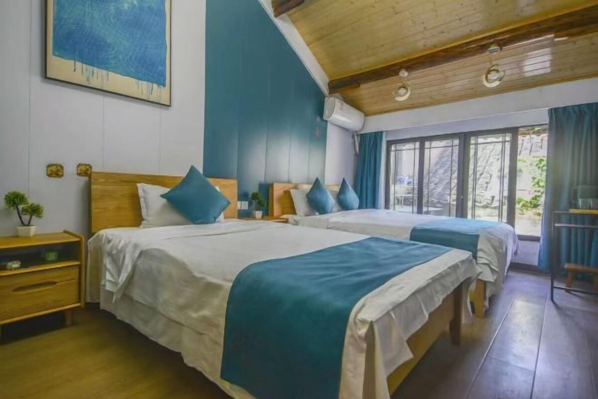 Une chambre avec deux lits, des têtes de lit en bois, un plafond en bois et une fenêtre avec des rideaux.