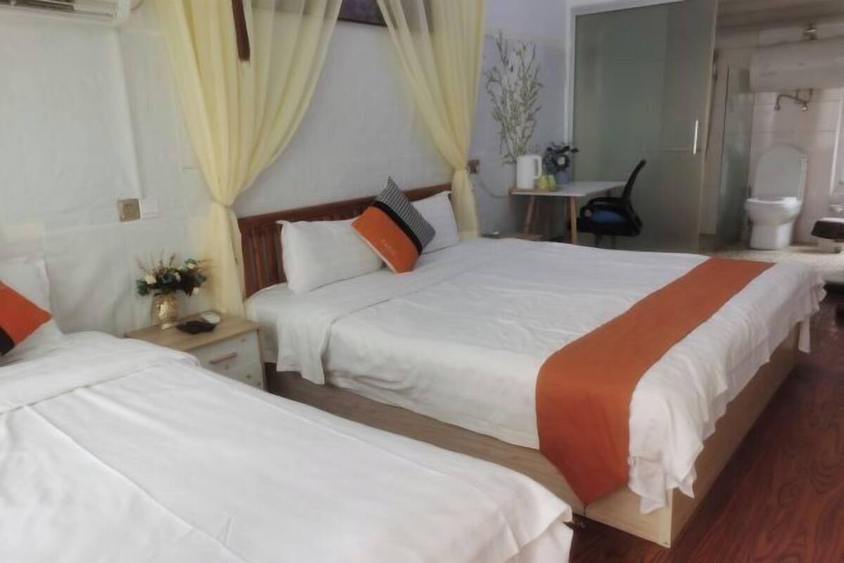 A hotel room with two beds, a desk, a chair, and a bathroom.