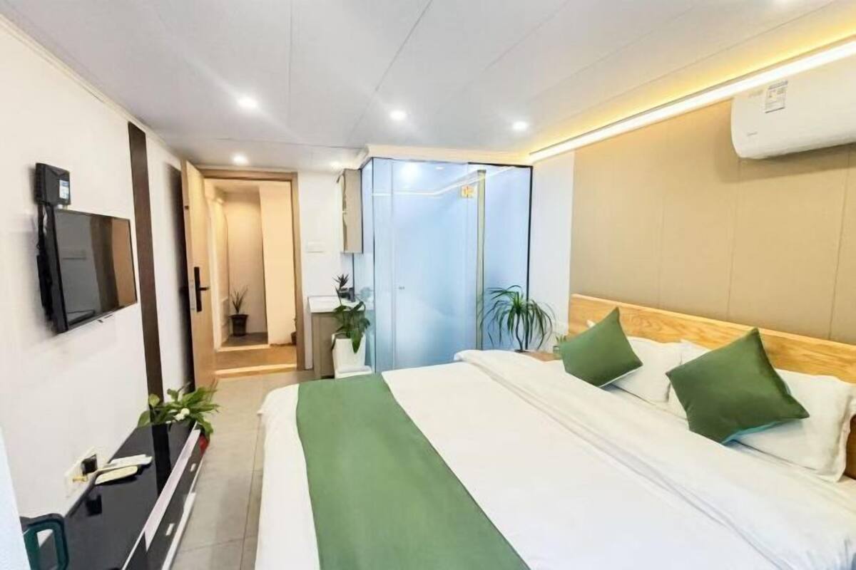A hotel room with a bed, a desk with a computer, a TV, and a bathroom door.