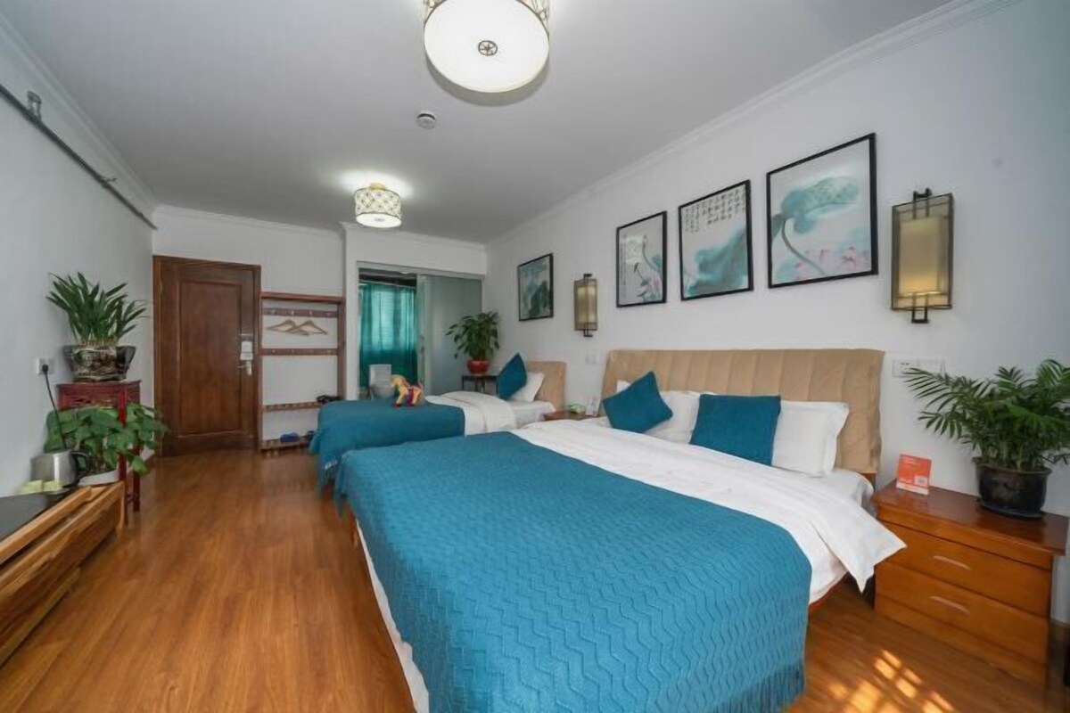 Habitación de hotel con dos camas, piso de madera y varias plantas en macetas.