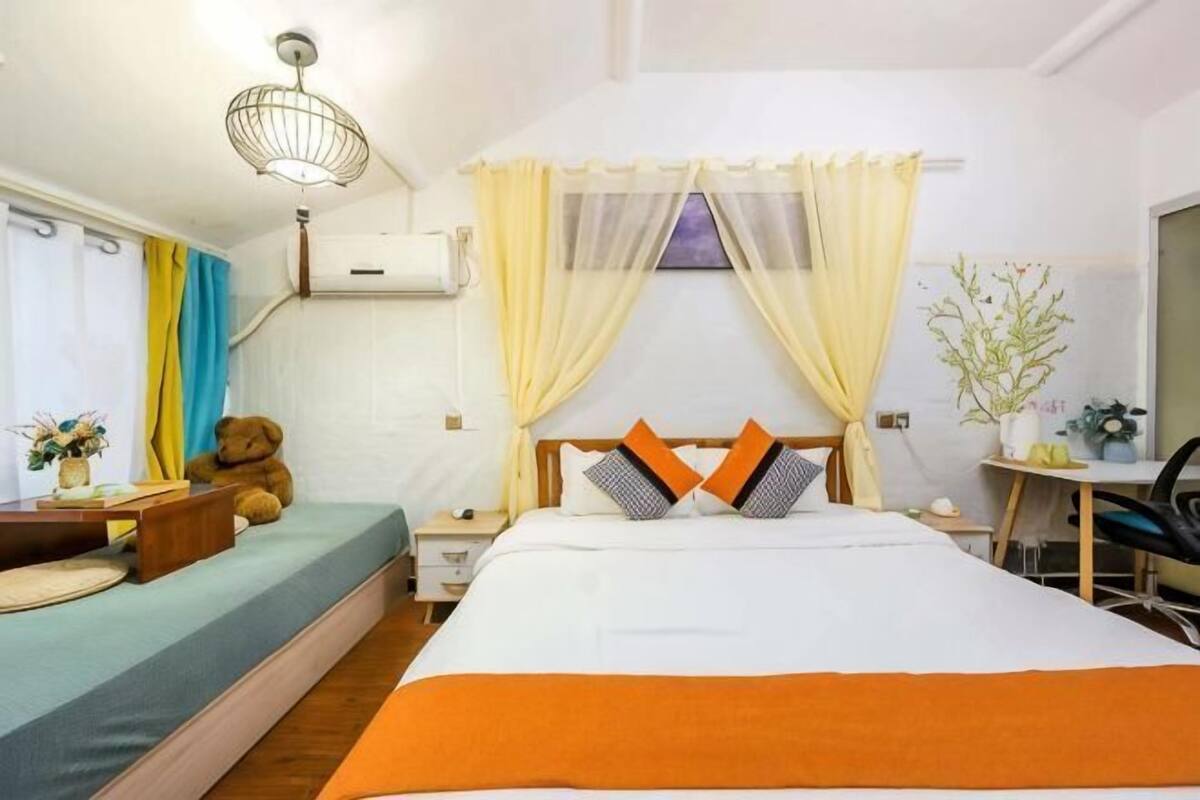 A bedroom with a bed, bedside table, lamp, and a teddy bear.