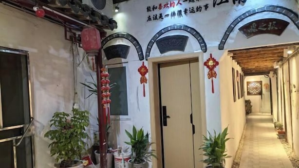 A hallway with a wooden door, potted plants, and a red lantern. - Tongli Ancient Town Forest Journey Design B&B (Suzhou)