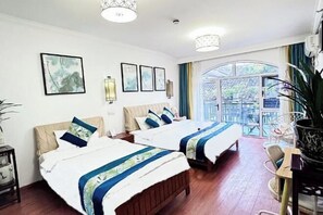 A hotel room with two beds, a large window with a view, and a dining area with chairs.