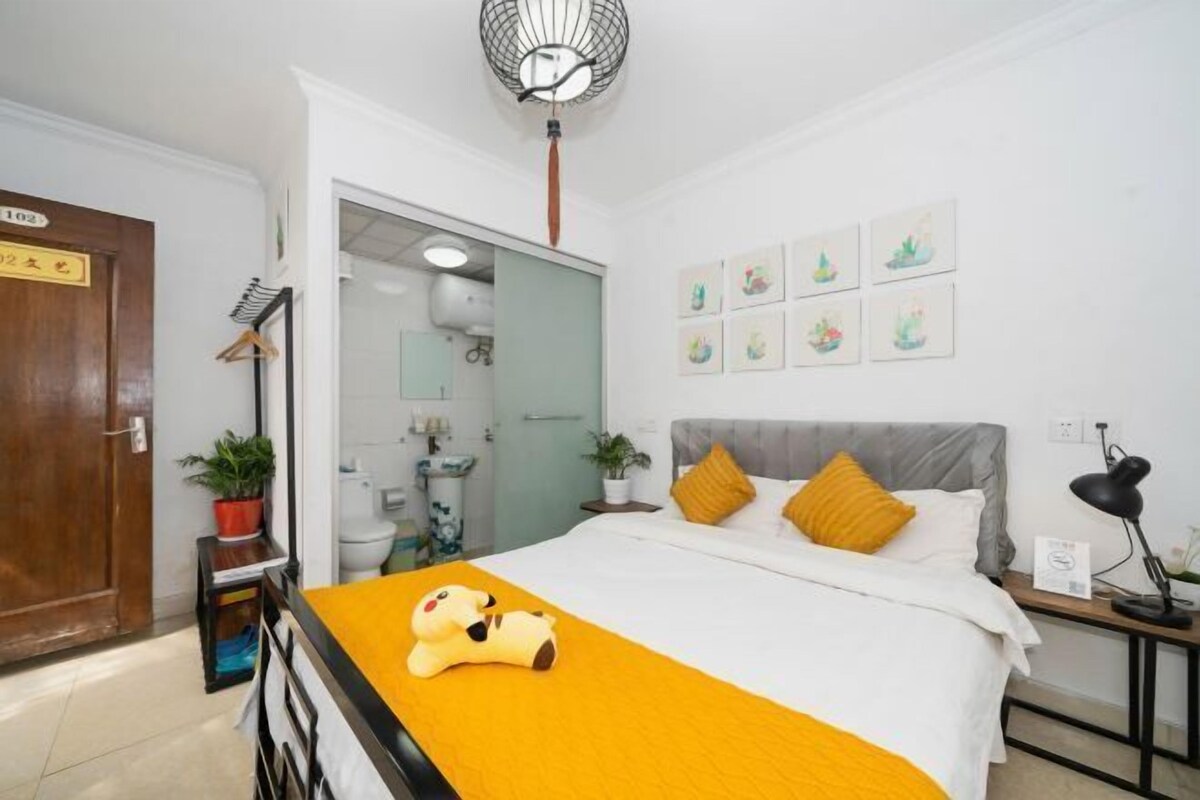 Un dormitorio con una cama, una mesita de noche, una lámpara y una pared decorada con cuadros.