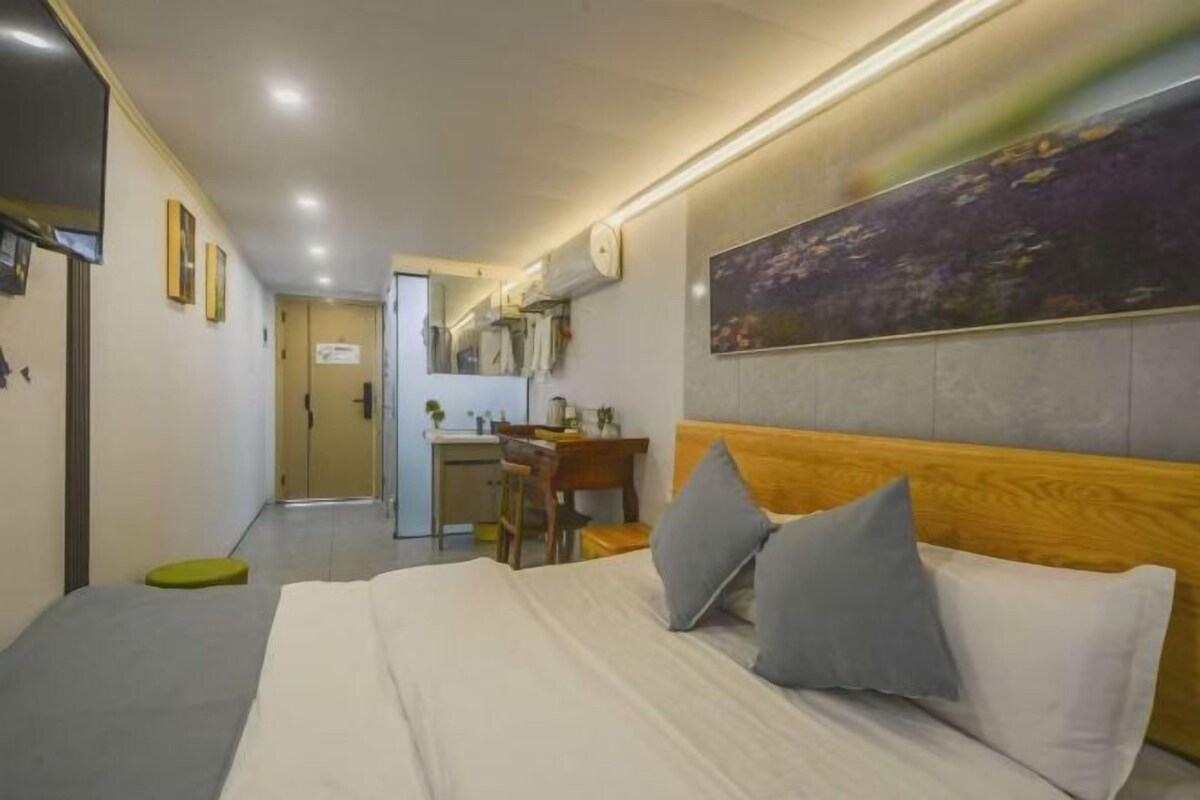 Une chambre d’hôtel avec un lit, un bureau et une chaise. Une porte donne accès à la salle de bain.