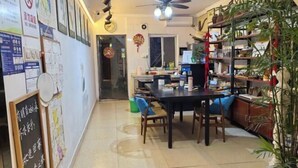 A dining area with a table and chairs, a ceiling fan, and a bookshelf with plants. - Tongli Ancient Town Forest Journey Design B&B (Suzhou)