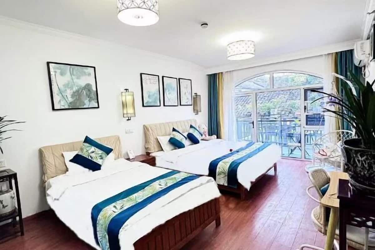 A hotel room with two beds, a large window, and a view of the outdoors.