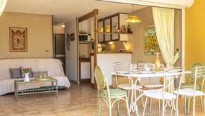 Una sala acogedora con un sofá, una mesa de comedor con sillas y una cocina al fondo.