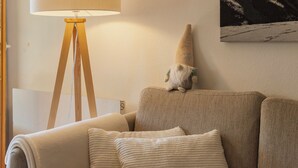 A room with a lamp on a tripod stand, a sofa with cushions, and a wall-mounted picture. - Chalet Anita by Interhome (Zweisimmen)