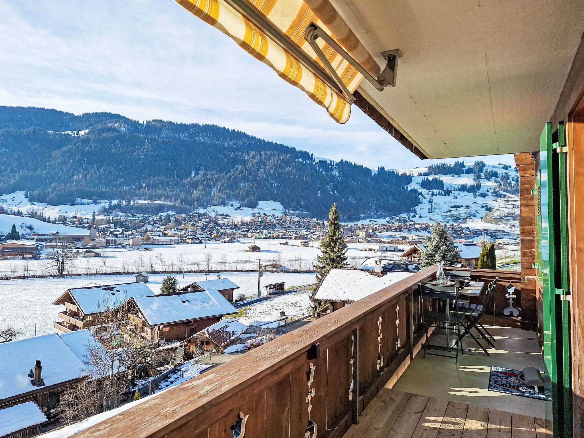 Ein Balkon mit Blick auf eine verschneite Stadt und Berge.