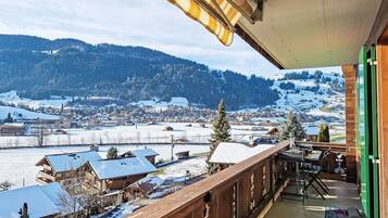Ein Balkon mit Blick auf eine verschneite Stadt und Berge.