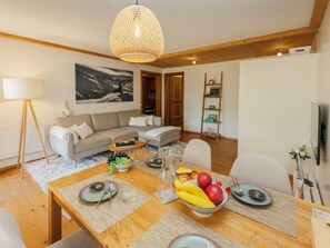 Ein modernes Wohnzimmer mit Essbereich, einer Couch, einem Couchtisch und einem Bild an der Wand.