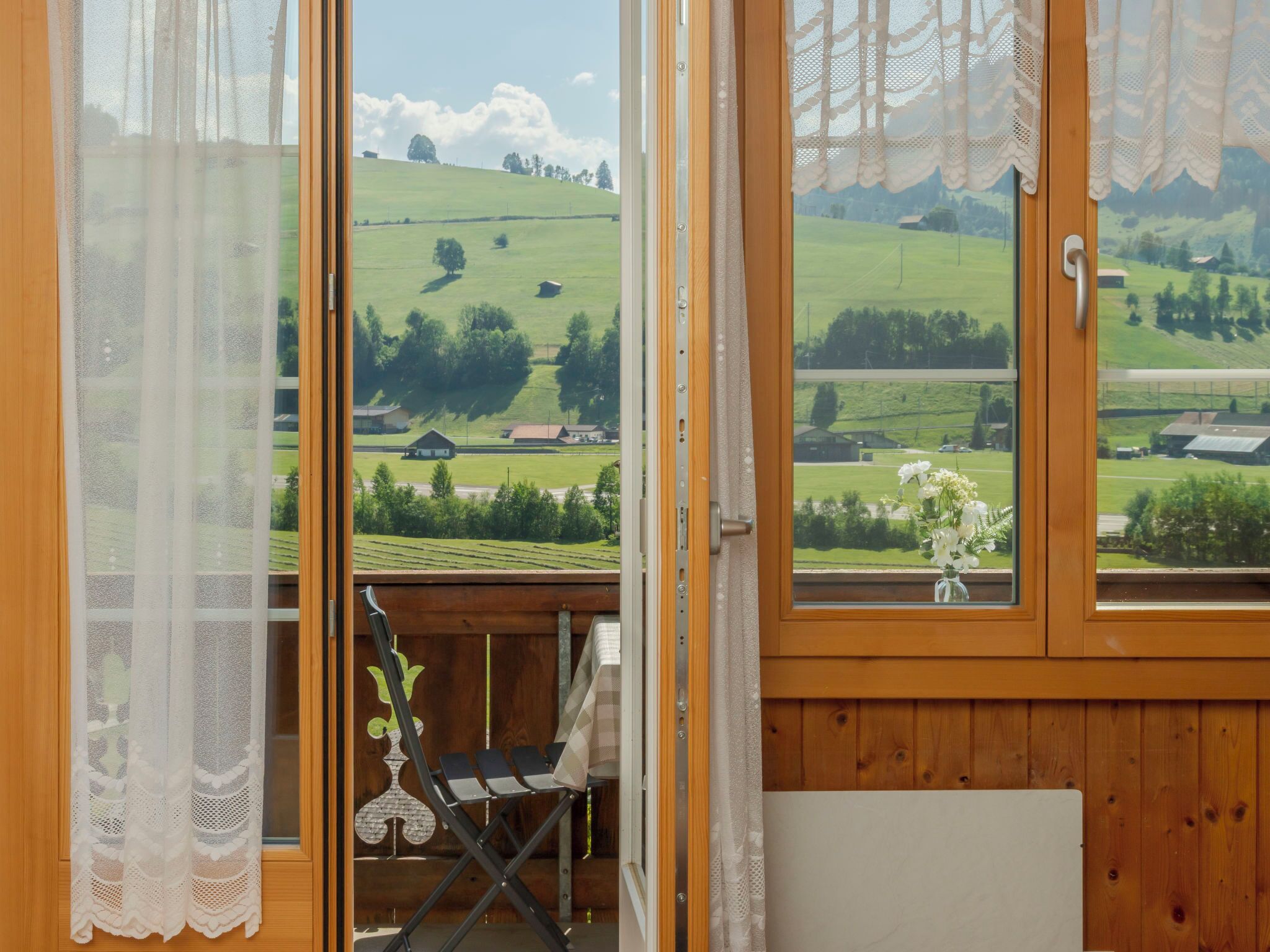 Ein Zimmer mit Holzvertäfelung, Blick auf eine grüne Landschaft und ein kleiner Tisch mit einem Stuhl.