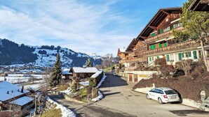 A traditional wooden building with balconies, a snow-covered landscape, and a clear sky. - Chalet Anita by Interhome (Zweisimmen)