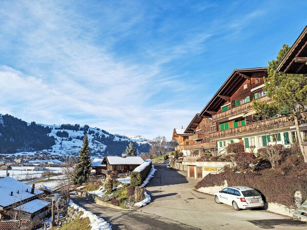 A traditional wooden building with balconies, a snow-covered landscape, and a clear sky.