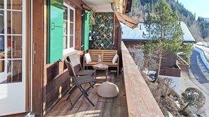 Ein Holzbalkon mit einer Bank, Stühlen und einem kleinen Tisch.