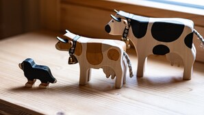 Ein Holztisch mit drei kühenförmigen Skulpturen.