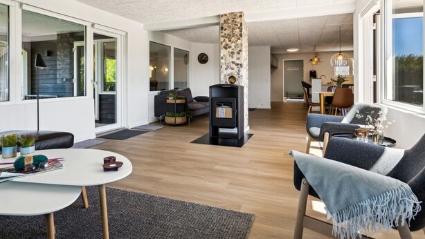 Amplia sala de estar con chimenea, comedor y ventanas grandes.