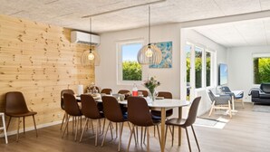 Un comedor moderno con una pared de madera, una mesa redonda y sillas marrones.