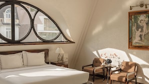 Une chambre à coucher avec un grand lit, un lustre, une fenêtre donnant sur un beau paysage et un tableau accroché au mur.
