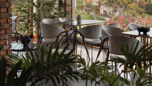 Un espace repas offrant une vue sur un paysage montagneux, avec un mur en briques, un lustre et plusieurs tables et chaises.