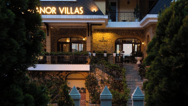 Un hôtel à la façade en pierre, doté d’un balcon avec des sièges d’extérieur et d’une enseigne indiquant « Landon Villas ».