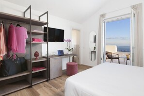Ett hotellrum med en säng, ett skrivbord med en tv, en garderob och en balkong med utsikt.