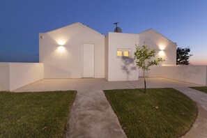 Ein modernes Haus mit weißer Fassade, einem kleinen Vorgarten und einem Weg zum Eingang.