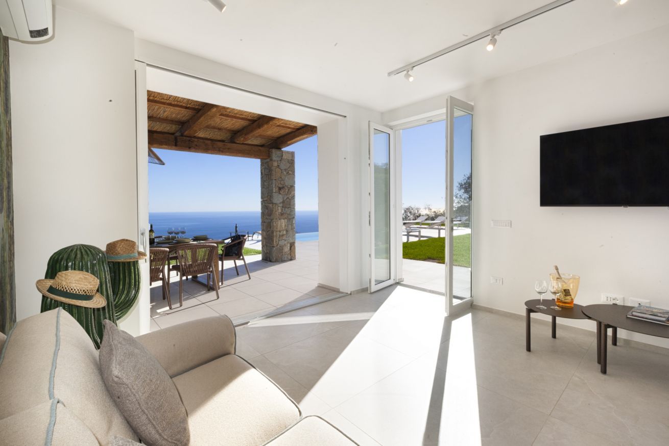 A modern living room with a sofa, a dining table, and a TV mounted on the wall.