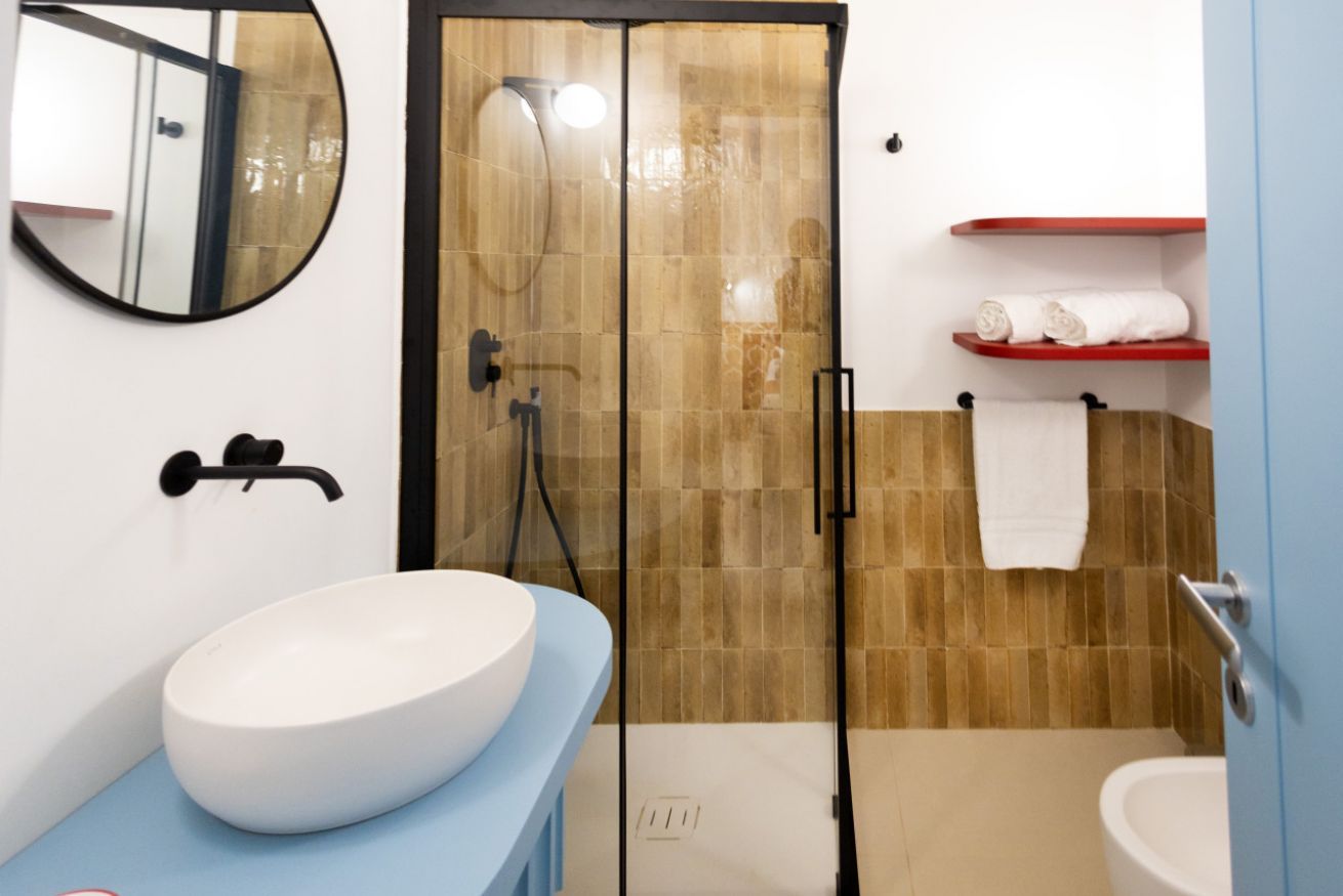 A bathroom with a white sink, a mirror, a shower enclosure, and a toilet.