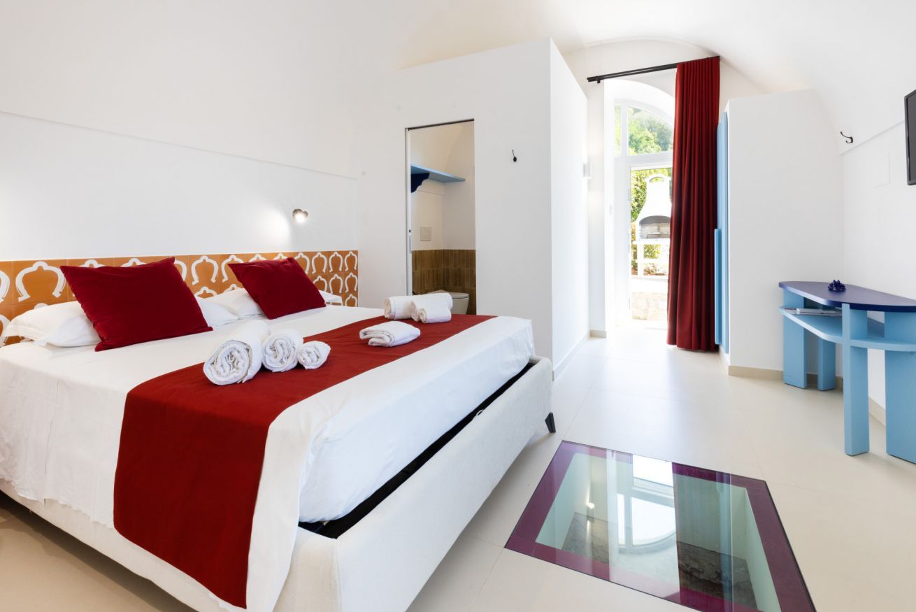 A hotel room with a large bed, a desk, and a glass table.