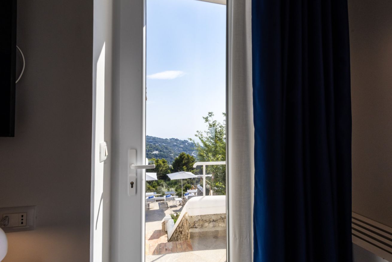Een kamer met uitzicht op een zwembad en bergen.