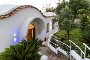 A modern house with a curved roof, white walls, and a stone pathway leading to the entrance. - MyExclusiveItaly - Elegant Villa in Anacapri | Infinity Pool & Design (Anacapri)
